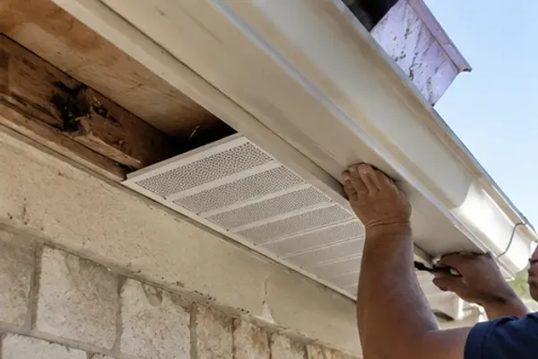 New fascia trim and vented soffit being installed under a roof edge